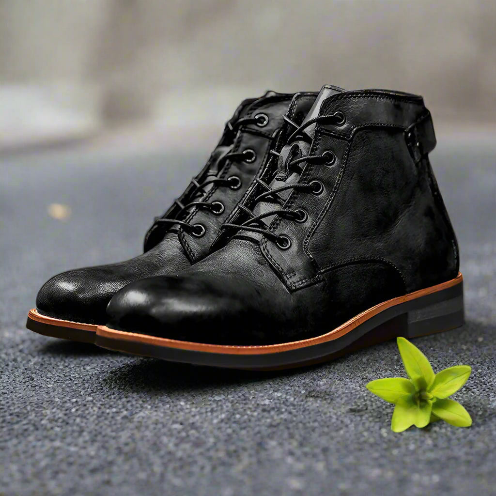 Black leather boots with brown soles on a wooden surface