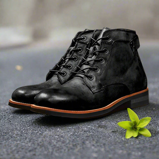Black leather boots with brown soles on a wooden surface